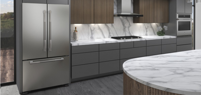 Une cuisine équipée d'un réfrigérateur JennAir, d'une table de cuisson JennAir, d'une hotte de cuisine JennAir et d'un four mural JennAir. Au premier plan, on voit un îlot et, sur les comptoirs près de la table de cuisson, une bouteille de vin et une plante.